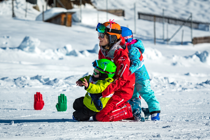 A ski instructor picks up one young skier as she receives a hug from another at the Kids Village in Grindelwald